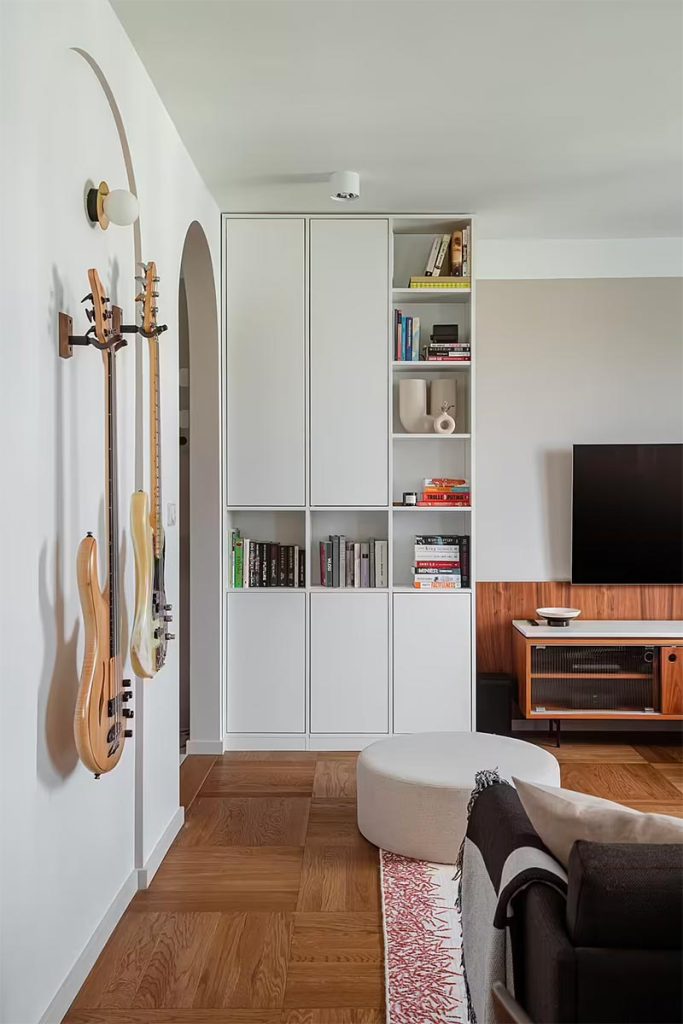 Raca Studio heeft dit modern vintage interieur ontworpen, waar een nieuwe vintage TV meubel gecombineerd is met een op maat gemaakte moderne boekenkast tot het plafond. | Fotografie: Hanna Połczyńska